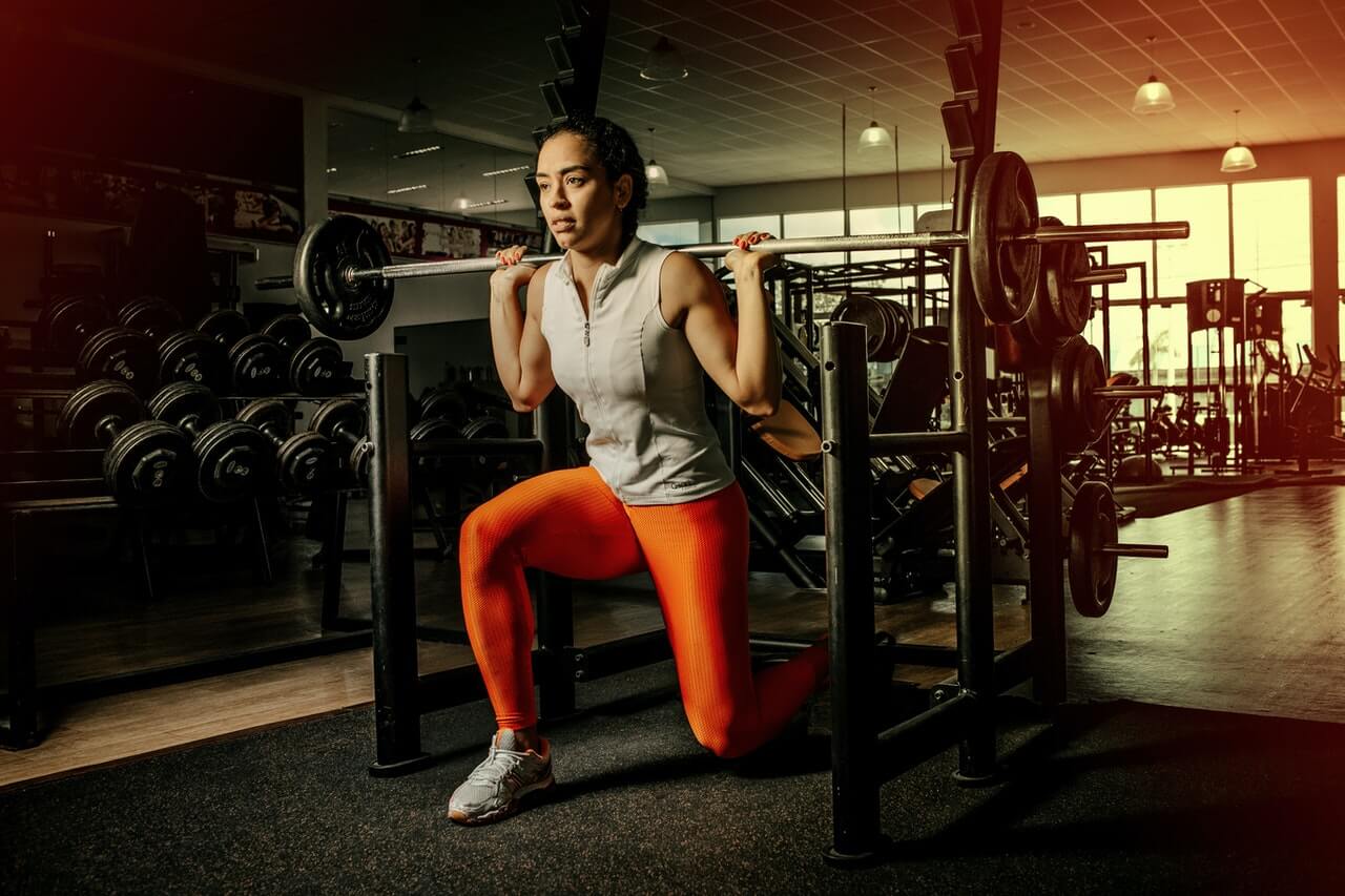 split squat in de sportschool door een vrouw met oranje legging