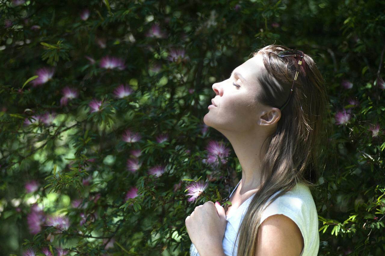 vrouw in de buitenlucht met paarse bloemen na het leven van tips om je sneller fit te voelen