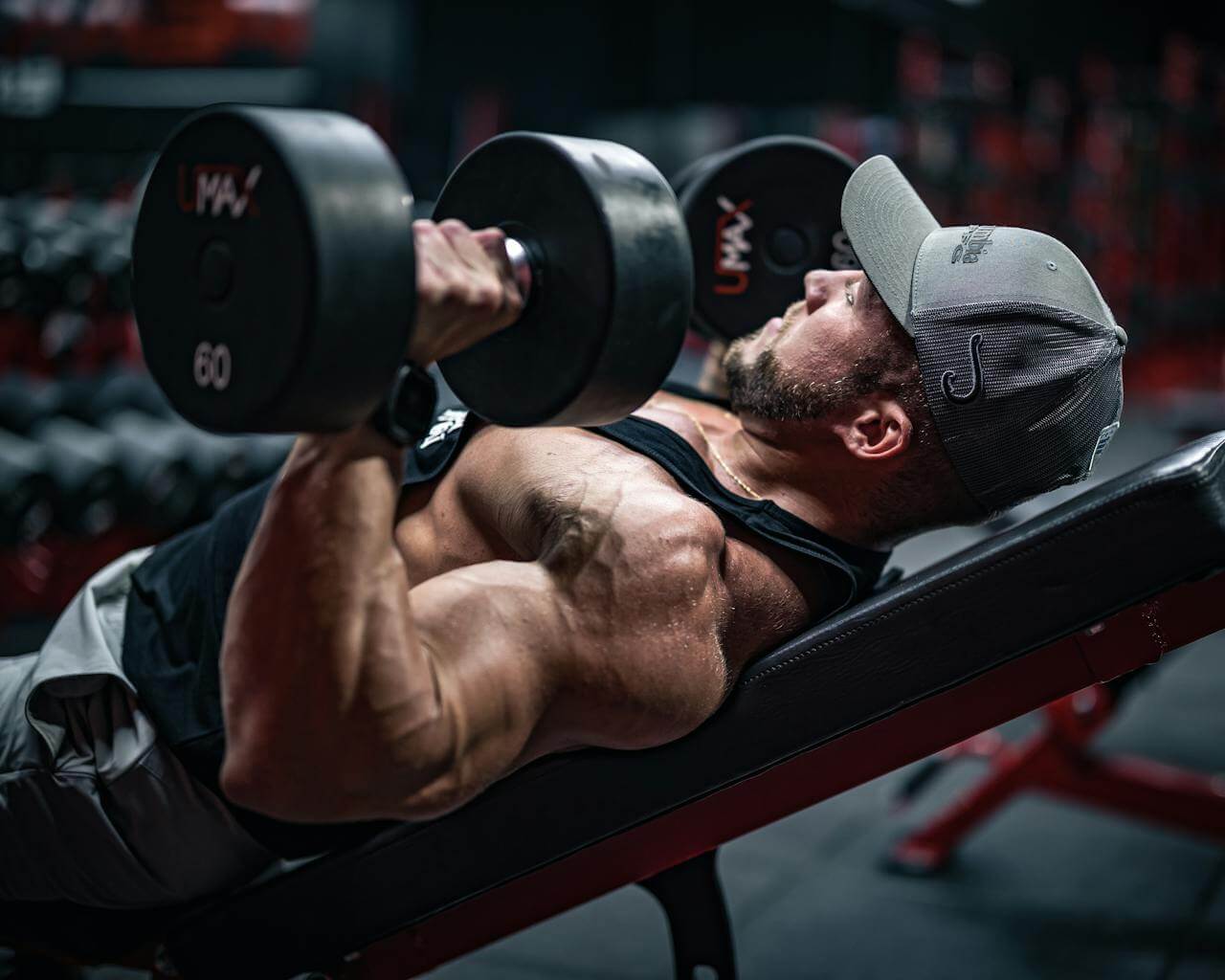 Man traint in sportschool met dumbbells na bepalen hoeveel sets per spiergroep