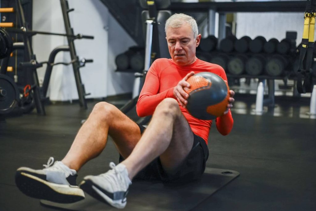 senioren man doet oefening voor fysiotherapie in sportschool