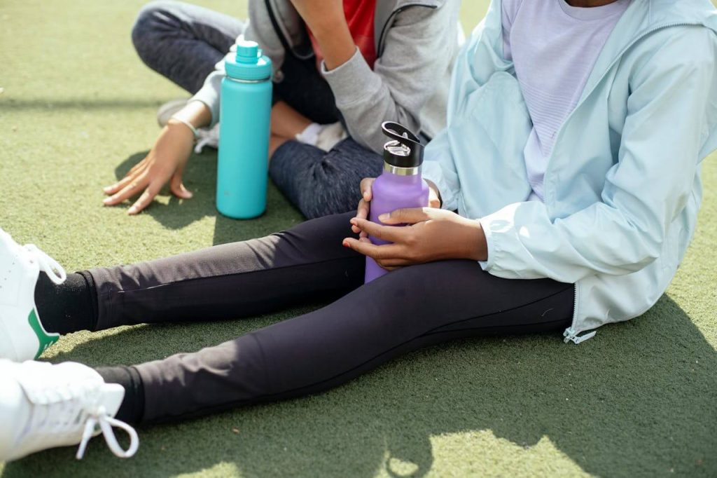 Twee sporten zitten samen op de grond met een sport bidon