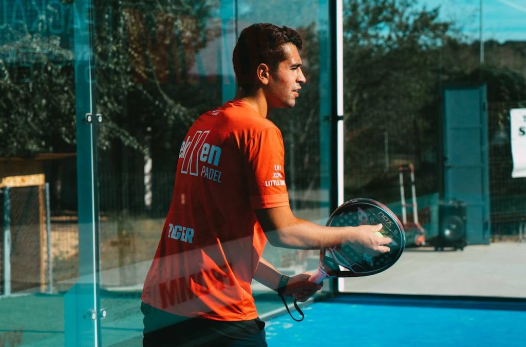 Man met oranje shirt speelt padel