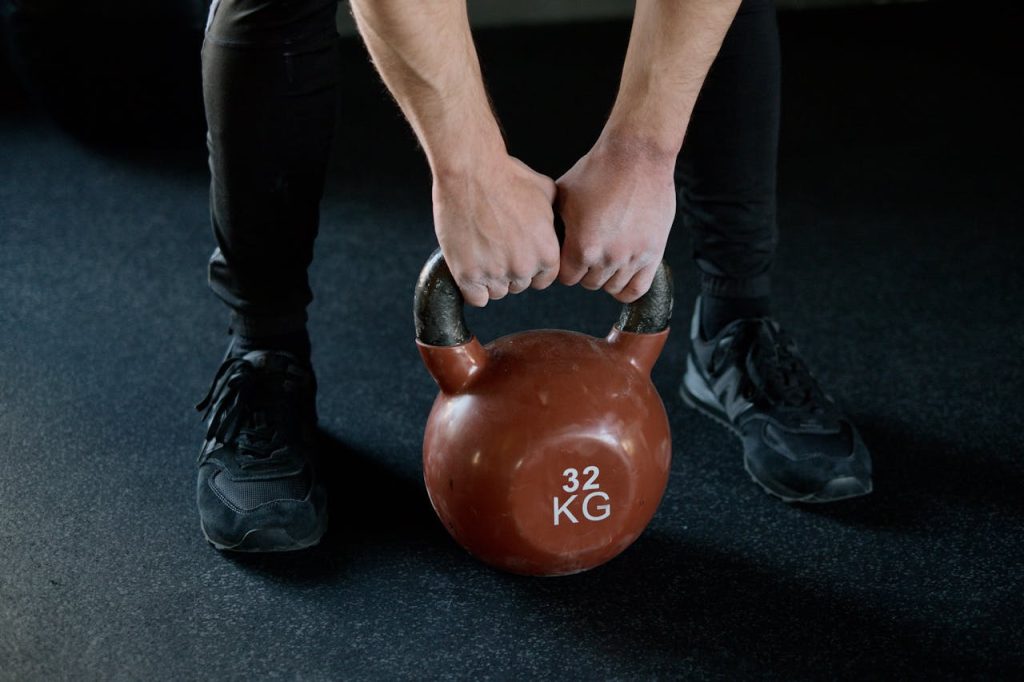 Man tilt een rode kettlebell van de grond