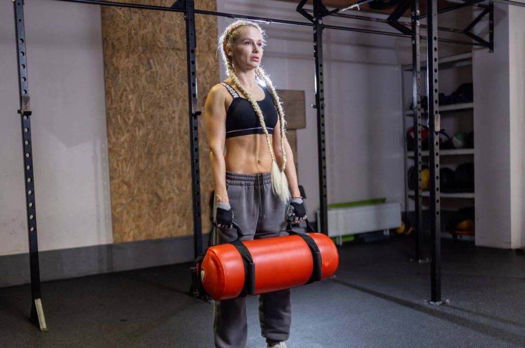 Vrouw traint met rode sandbag