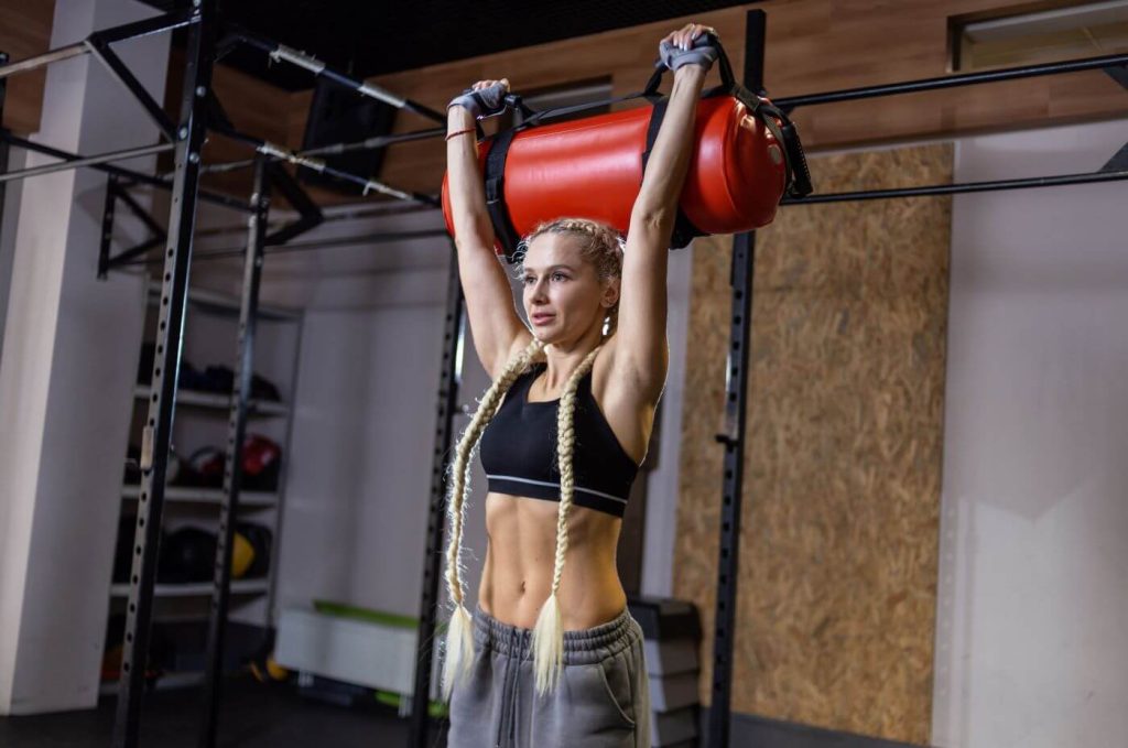 sandbag in rode kleur opgetild door sportieve vrouw